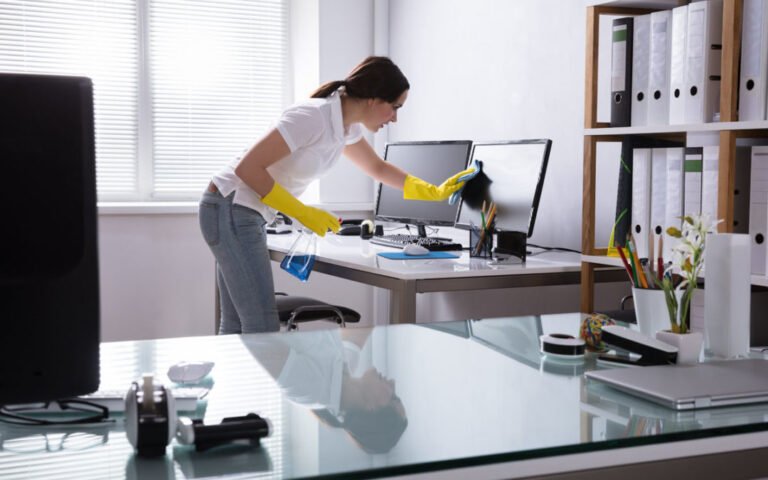 Young Woman Cleaning Computer With Rag In Office